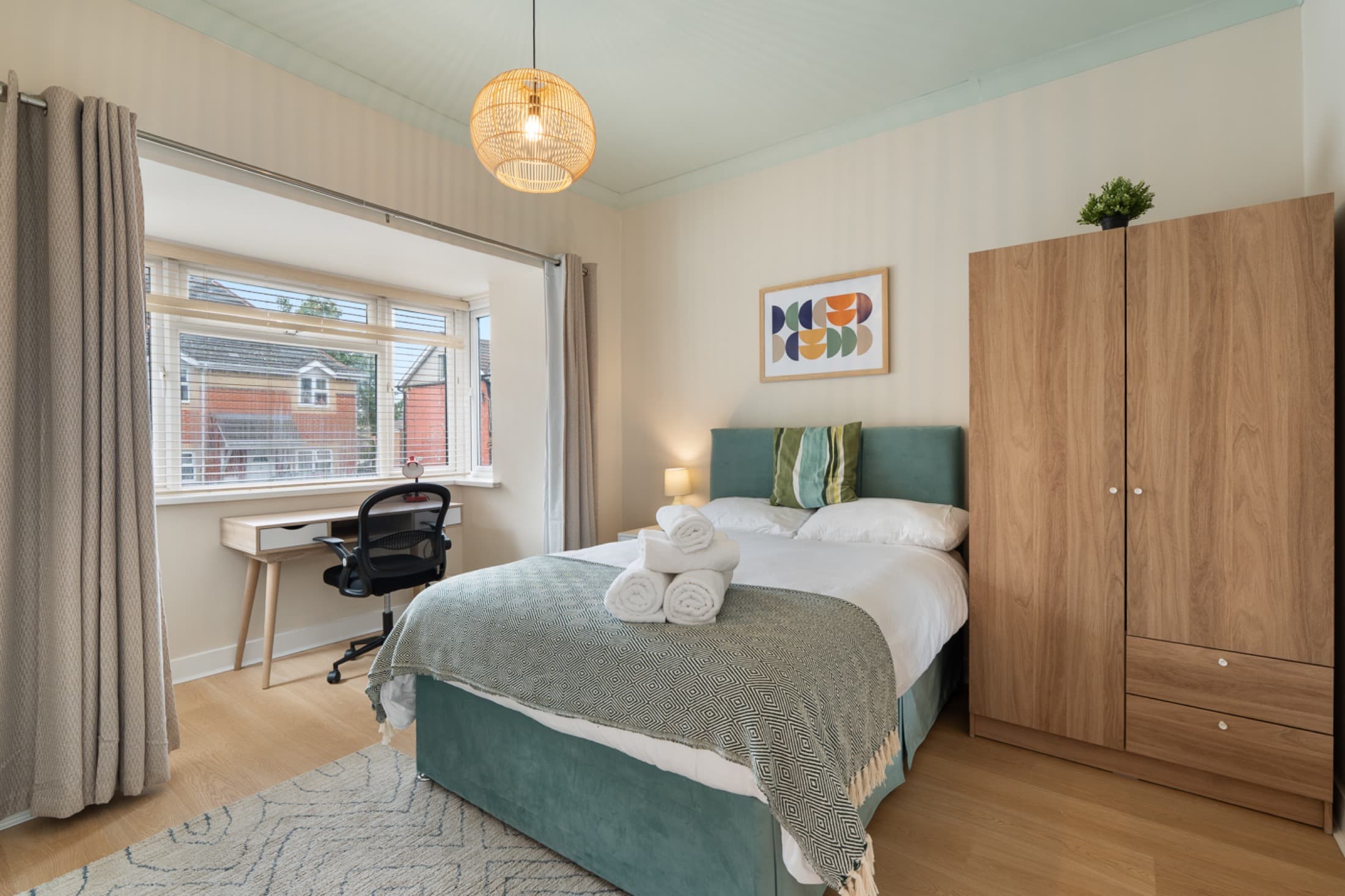 Well-presented bedroom with desk, chair, and soft furnishings